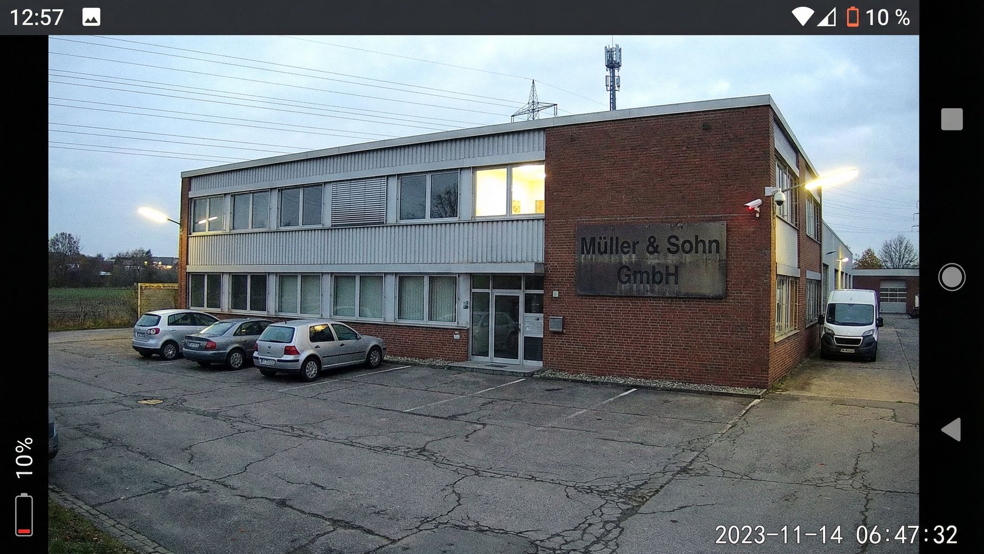 Industrial building on the outskirts with power lines and surveillance camera, symbolic of unprotected digital infrastructure